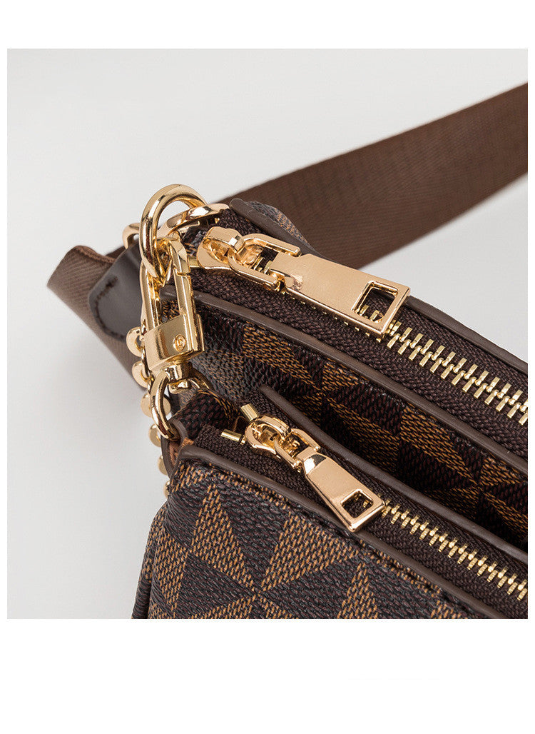 Close-up of a brown leather handbag with gold zippers and hardware on a light gray background