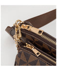 Close-up of a brown leather handbag with gold zippers and hardware on a light gray background