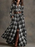 Woman wearing a long plaid dress with a belt and brown boots against a gray background