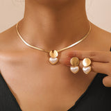 Gold necklace and heart-shaped earrings on a model against a neutral background