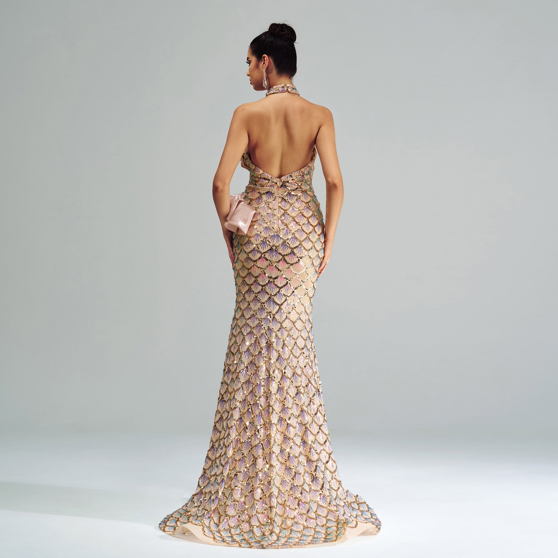 Woman wearing a gold evening gown with a textured pattern on a gray background