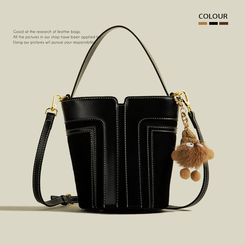 Black leather handbag with a decorative keychain on a beige background