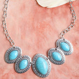 Necklace with turquoise stones and silver chain on a pink background